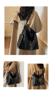 Detail of a large black hobo tote bag featuring fine leather texture and a small pouch