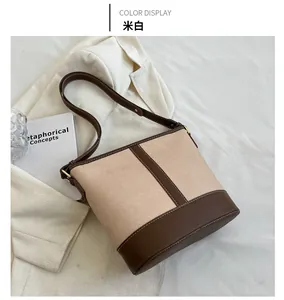 Close-up of cream canvas and brown leather bucket bag with top stitching details