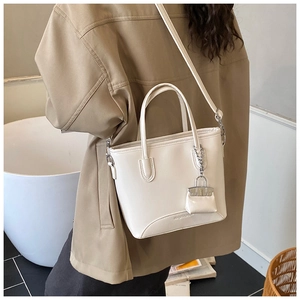 Detail of cream PU leather bucket bag featuring a mini pouch charm and subtle texture