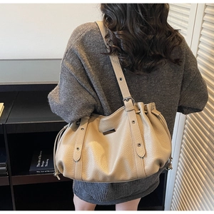 Detail of beige litchi grain leather tote bag with drawstring sides and adjustable strap