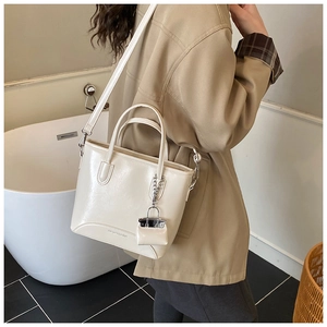 Detail of cream crossbody bucket bag with pebble leather texture and mini coin purse