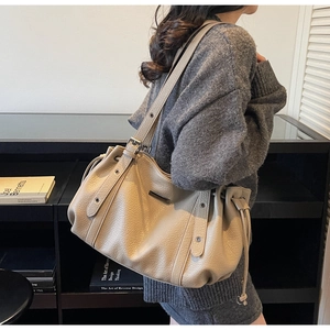 Detail of khaki leather tote bag with side drawstring and soft litchi texture