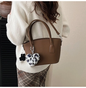 Detail of brown litchi pattern leather bucket bag with a leopard heart plush charm