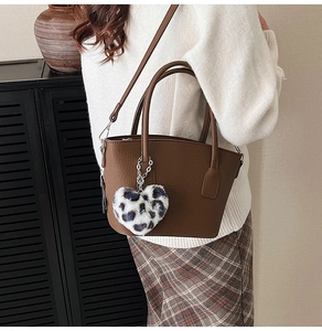 Detail of dark brown leather handbag with unique blue leopard heart plush pendant