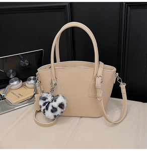 Detail of beige pebbled leather tote with a stylish leopard print heart charm and dual handles