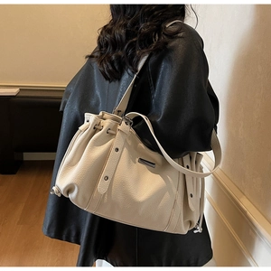 Detail of off-white lychee texture leather tote bag with drawstring and rivets
