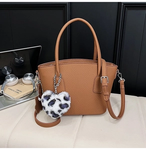 Caramel lychee grain handbag with leopard heart charm in a minimalist urban setting