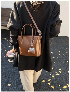 Detail view of a vintage brown leather bucket bag with a mini pouch on a long strap