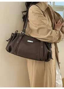 Detail of dark brown leather underarm bag with silver plaque and side drawstring decor