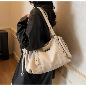 Close-up of off-white lychee pattern leather tote bag with silver rivets and drawstrings