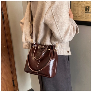 Braune Eimer-Tasche aus Ölwachs-Leder mit modischem, breitem gewebtem Schultergurt am Model