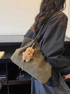 Olive green suede tote bag with contrast stitching and plush dog charm accessory