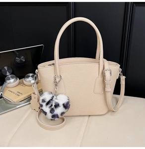 Detail of beige lychee pattern PU leather handbag with heart leopard fur charm