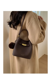 Vue détaillée du sac seau en cuir marron avec fermoir doré et accessoire pompon