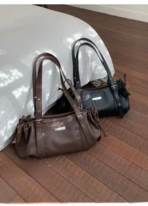 Close-up of litchi texture leather tote bags in brown and black with metal eyelets