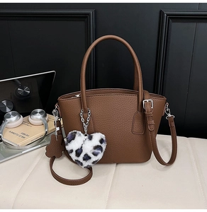Brown lychee textured leather bag with heart leopard pendant in office setting