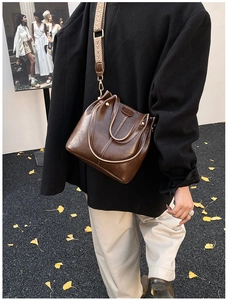 Detail einer braunen Vintage-Leder-Eimertasche mit einem gewebten breiten Schultergurt