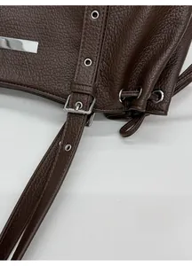 Detail of dark brown lychee leather texture with adjustable silver metal buckle and strap