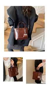 Detailed macro view of a brown glossy leather bucket bag with a small lock charm accessory