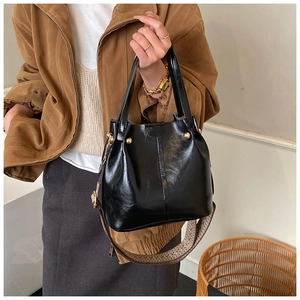 Détail du sac seau en cuir noir avec clous dorés et bandoulière jacquard ethnique