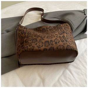 Close-up of leopard print tote bag with dark brown leather details and adjustable strap
