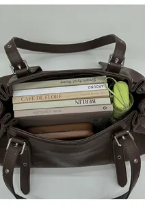 Top view of spacious interior of dark brown leather handbag with books and accessories
