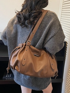 Brown pebble leather tote bag with drawstring details and adjustable shoulder strap