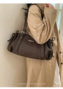 Detailed macro view of dark brown pebbled leather texture and adjustable buckle on shoulder bag