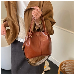 Détail du sac seau marron avec bandoulière ethnique tissée et texture en cuir vintage poli