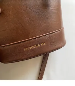 Close-up of brown litchi pattern leather with gold FASHION & YM embossed logo detail