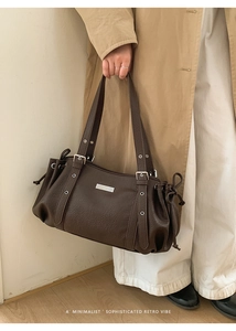 Close-up of brown faux leather shoulder bag with lychee texture and metal hardware details