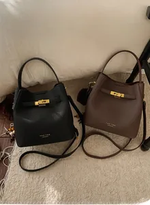 Détail de sacs seaux en cuir minimalistes noir et marron avec fermoirs rotatifs en métal