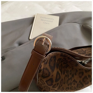 Detail of leopard print shoulder bag with brown leather strap and silver metal buckle