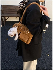 Detail of dark brown suede vintage bowling bag with pockets and cute rabbit pendant