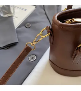Close-up of golden metal lobster clasp and ring on a brown leather bucket bag