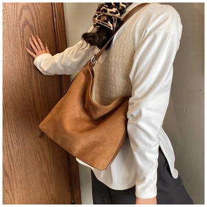 Brown frosted leather tote bag with silver buckle worn by a model in a warm autumn setting