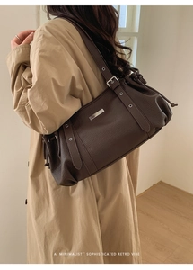 Detail of dark brown leather bowling shoulder bag with silver eyelets and drawstring