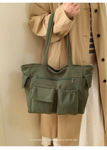 Detail of olive green corduroy tote bag with multiple pockets shown on model