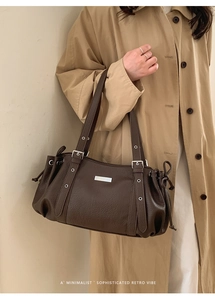 Detail of dark brown lychee grain leather handbag with silver grommets and retro design
