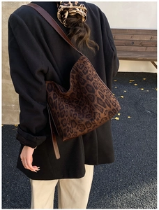 Detail view of large leopard print hobo bag with dark brown leather shoulder strap in use