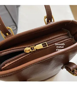 Close-up of golden zipper hardware on brown pebbled leather bucket bag handle