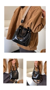Detail der schwarzen Leder-Beuteltasche mit Goldnieten und gemustertem breitem Gurt