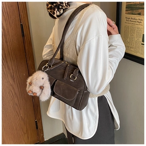 Detail of coffee brown retro shoulder bag with plush bunny charm and dual front pockets