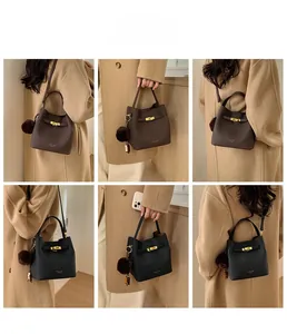 Sac à main élégant en cuir pour femme avec fermoir doré et pompon sur une tenue chic