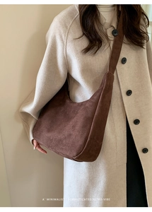 Detail of minimalist coffee brown suede tote bag with retro moon shape on model