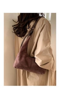 Retro brown suede shoulder bag on model wearing trench coat in minimalist setting