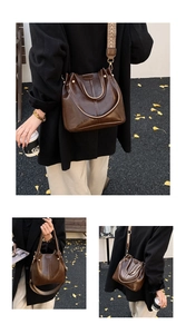 Detail der dunkelbraunen Leder-Eimertasche mit Retro-Nieten und breitem Mustergurt