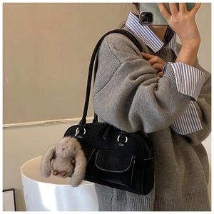 Close-up of vintage black bowling bag with white stitching and plush rabbit pendant