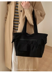 Close-up of black corduroy tote bag showing multiple functional pockets and soft texture