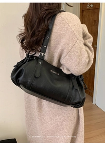 Black leather shoulder bag with drawstring detail shown on model in a retro style